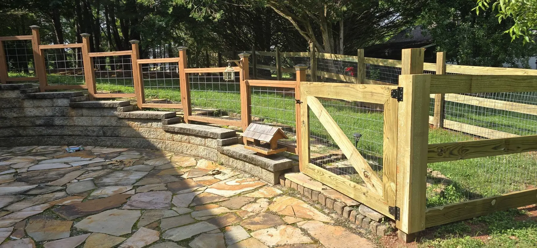 Completed wood post-and-rail fence with wire mesh and custom gate