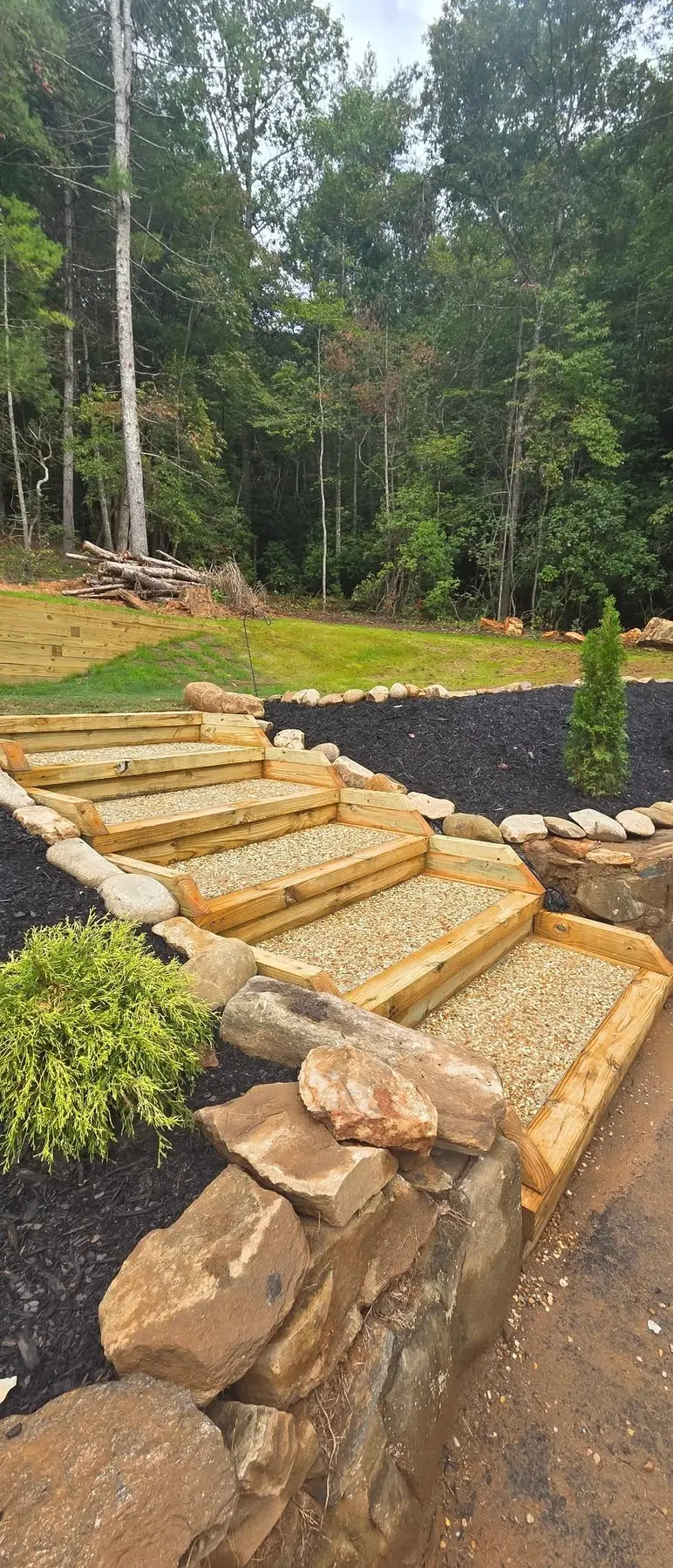 Angled view of landscape steps bordered by natural stone and planting beds