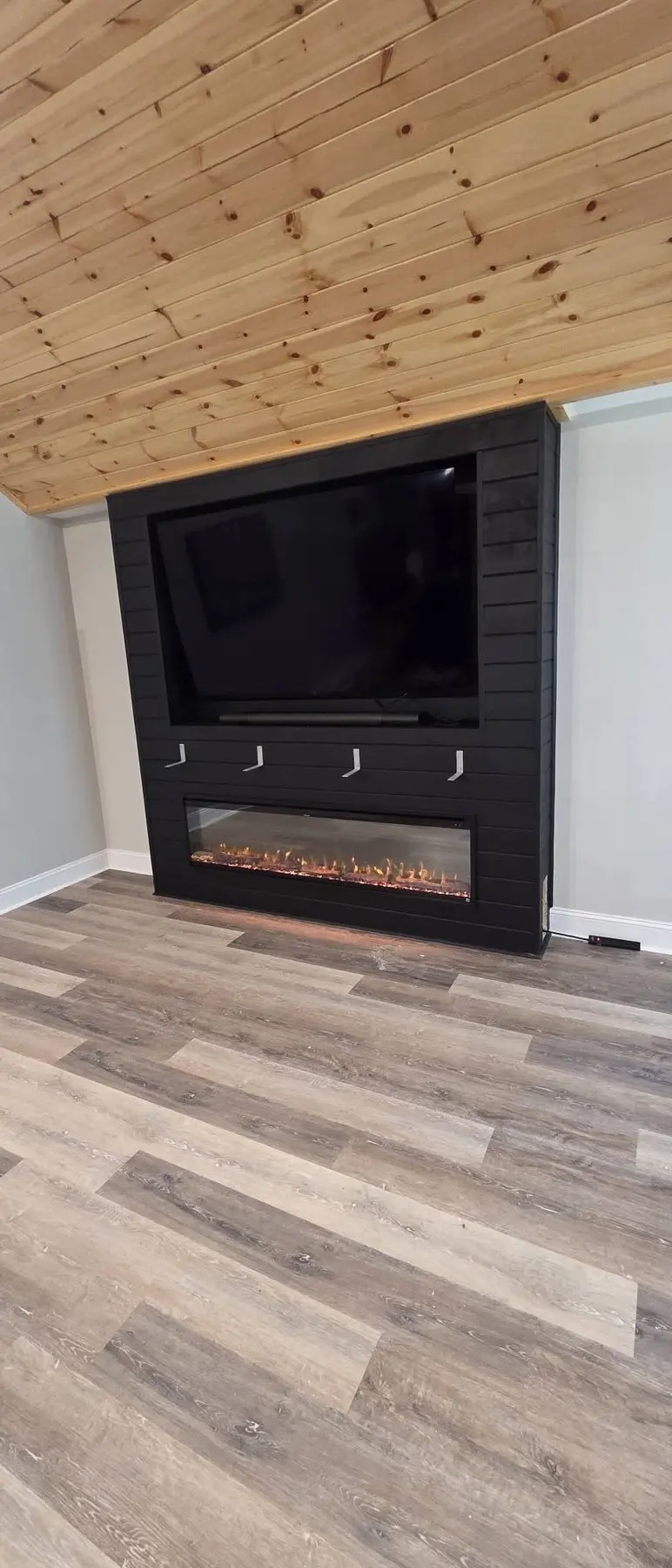 Television and electric fireplace installed in the custom black feature wall