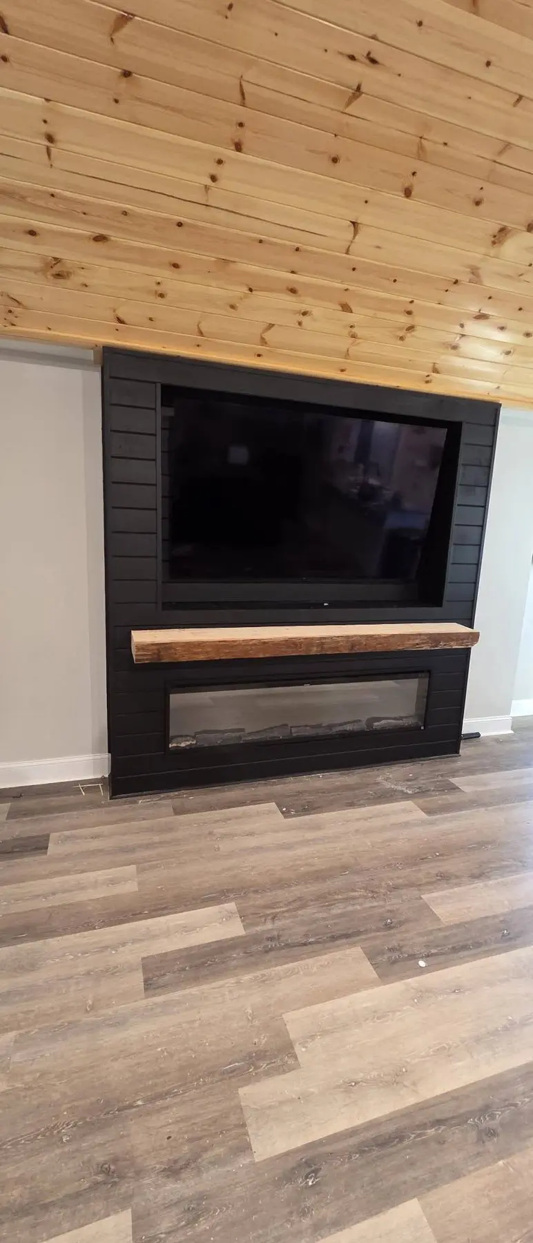 Completed custom TV and electric fireplace feature wall with rustic wood mantel